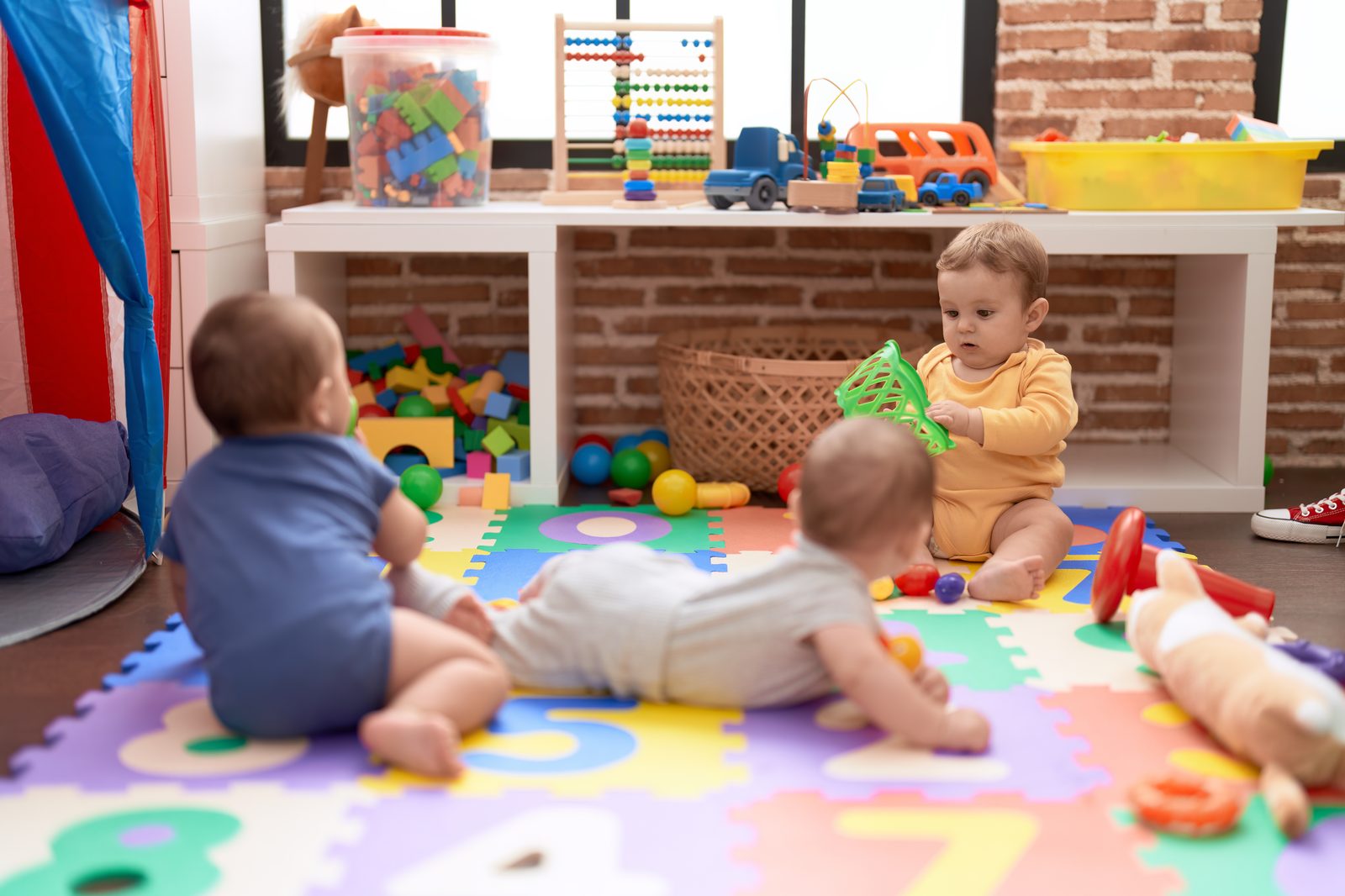 Infant room with colorful play areas and tree mural